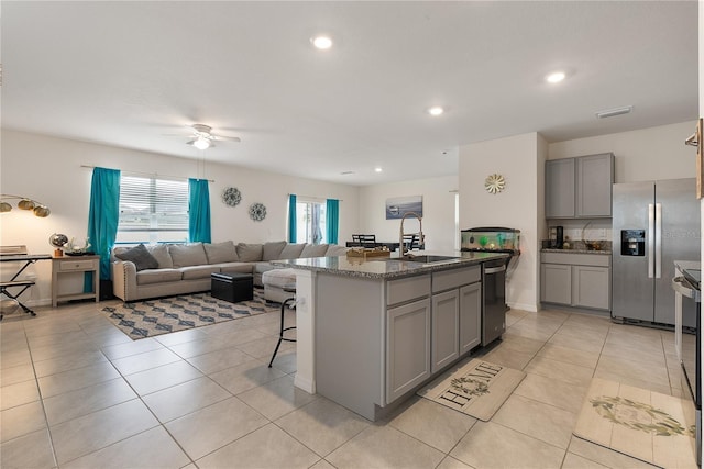 kitchen with a ceiling fan, gray cabinetry, a sink, open floor plan, and appliances with stainless steel finishes
