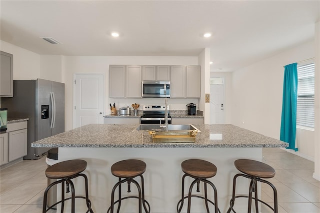 kitchen featuring gray cabinets, stainless steel appliances, light tile patterned flooring, and a sink