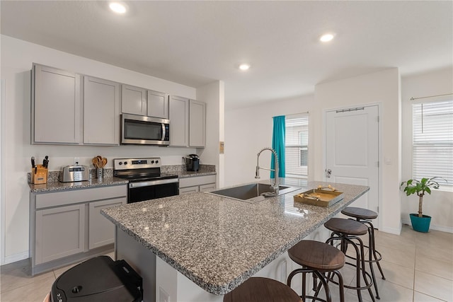 kitchen featuring appliances with stainless steel finishes, gray cabinets, light tile patterned floors, and a sink