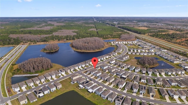 drone / aerial view with a wooded view, a water view, and a residential view
