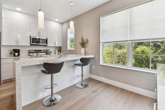 2547 Lexington Oak Dr, Brandon, FL 33511 - kitchen with appliances with stainless steel finishes, baseboards, light wood-style floors, white cabinets, and backsplash