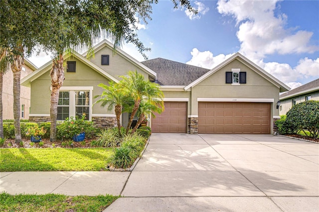 view of front of property with an attached garage, stone siding, and stucco siding