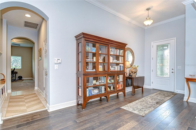 foyer with visible vents, arched walkways, baseboards, and wood finished floors