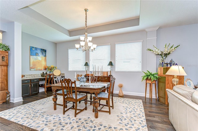 dining room featuring baseboards, dark wood-style flooring, a notable chandelier, and a tray ceiling