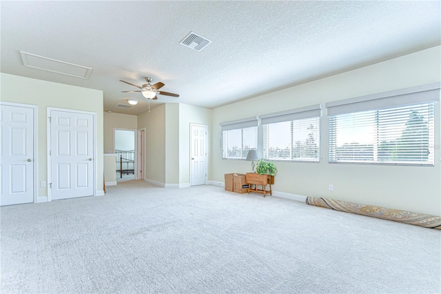 interior space featuring baseboards, ceiling fan, a textured ceiling, and visible vents