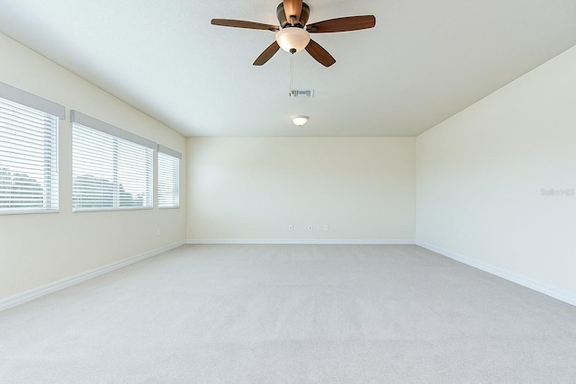 empty room with baseboards, a ceiling fan, light colored carpet, and visible vents