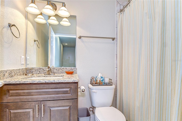 bathroom with toilet, a textured wall, a shower with curtain, and vanity