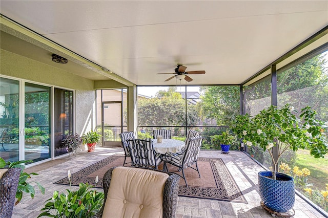 sunroom / solarium featuring plenty of natural light, a ceiling fan, and outdoor dining space