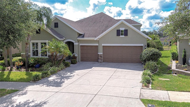 view of front of property with a shingled roof, a front lawn, stone siding, stucco siding, and concrete driveway