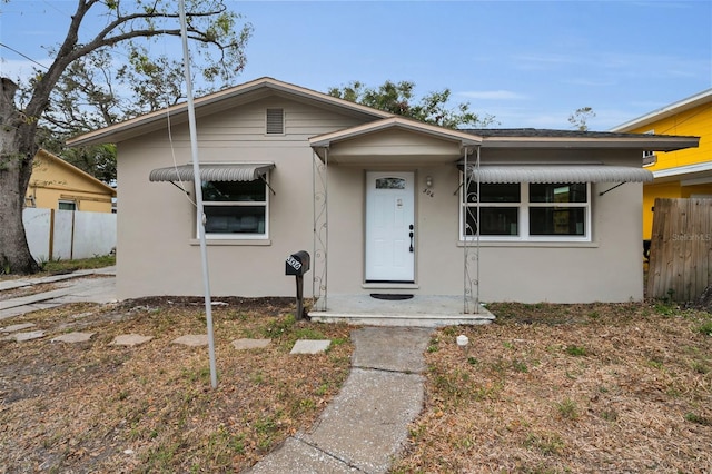 bungalow-style house with fence and stucco siding