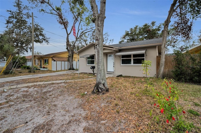 view of front facade featuring an outdoor structure, stucco siding, a storage shed, and fence