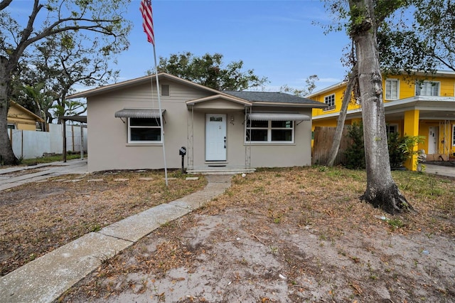 bungalow with fence and stucco siding