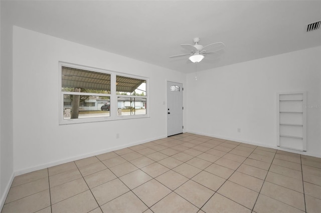 unfurnished room with visible vents, light tile patterned flooring, baseboards, built in shelves, and a ceiling fan