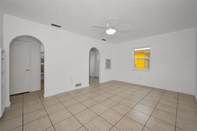 spare room featuring visible vents, arched walkways, a ceiling fan, and light tile patterned floors