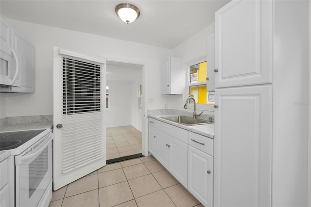 kitchen featuring a sink, light tile patterned floors, white cabinets, and white appliances