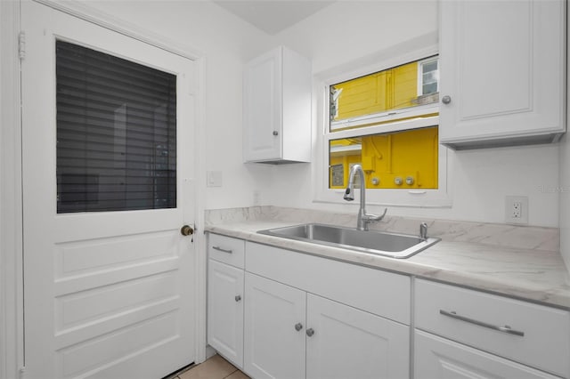 kitchen featuring white cabinets, a sink, and light countertops