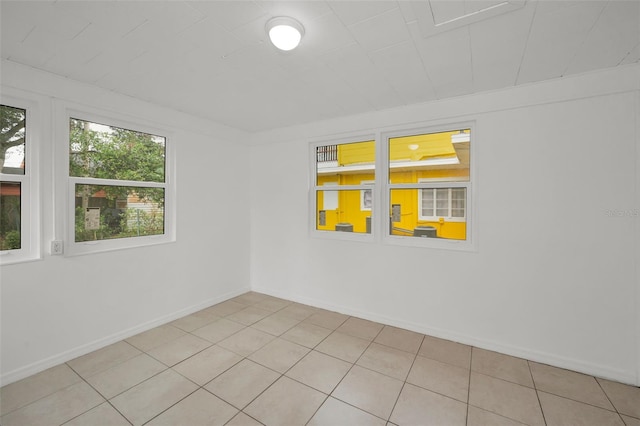 empty room featuring baseboards and light tile patterned flooring