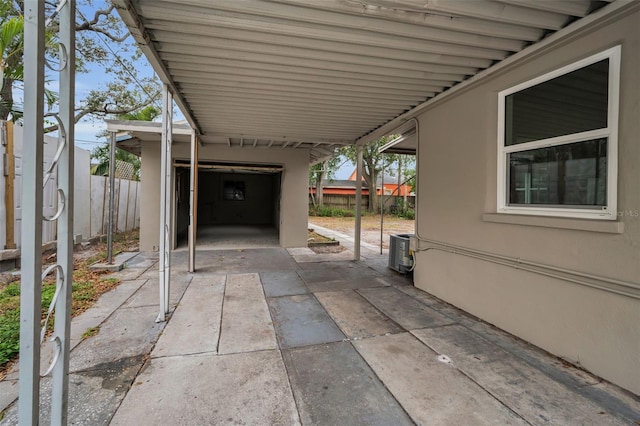 view of patio with cooling unit, fence, and a carport