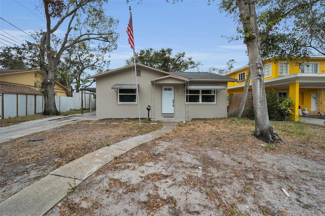 bungalow-style home featuring fence and stucco siding