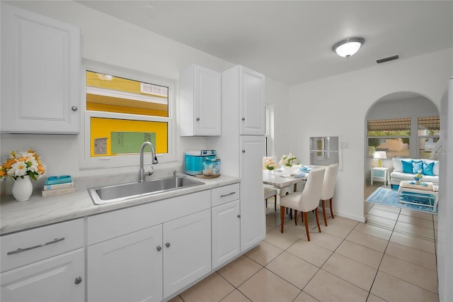 306 S Highland Ave, Clearwater, FL 33755 - kitchen featuring a sink, light countertops, light tile patterned floors, white cabinetry, and arched walkways