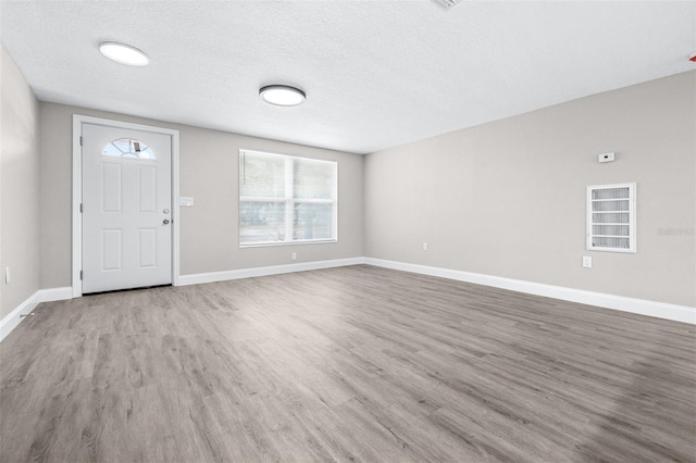 13926 Helen Ave, Hudson, FL 34667 - unfurnished living room featuring a textured ceiling, baseboards, and wood finished floors