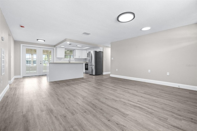 13926 Helen Ave, Hudson, FL 34667 - unfurnished living room with french doors, visible vents, a sink, baseboards, and light wood finished floors