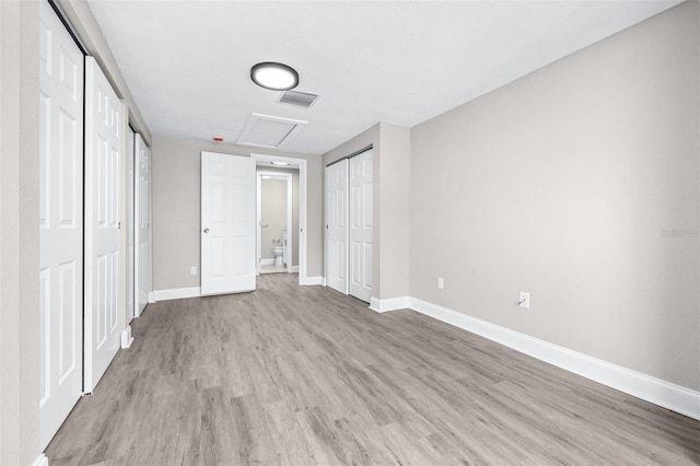 13926 Helen Ave, Hudson, FL 34667 - unfurnished bedroom with visible vents, multiple closets, baseboards, attic access, and light wood finished floors