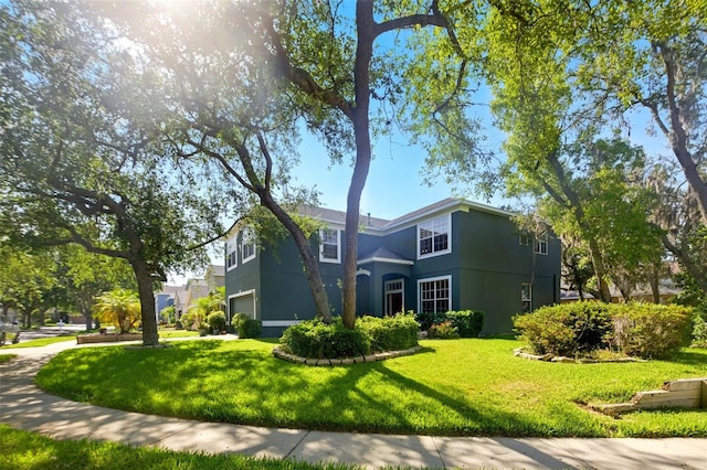 traditional-style home featuring stucco siding, a garage, and a front lawn