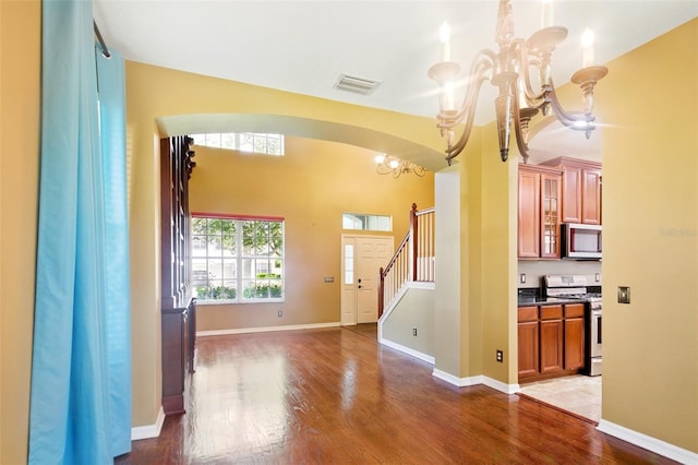 interior space featuring visible vents, wood finished floors, stairway, a chandelier, and arched walkways