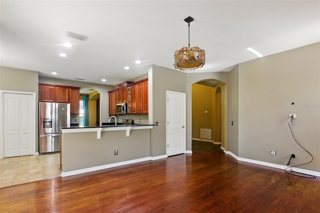 kitchen featuring a breakfast bar area, visible vents, arched walkways, a peninsula, and stainless steel appliances