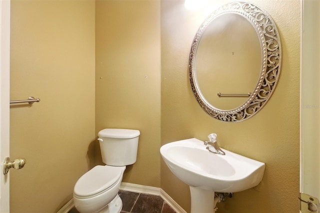 half bath featuring toilet, baseboards, a sink, and tile patterned flooring