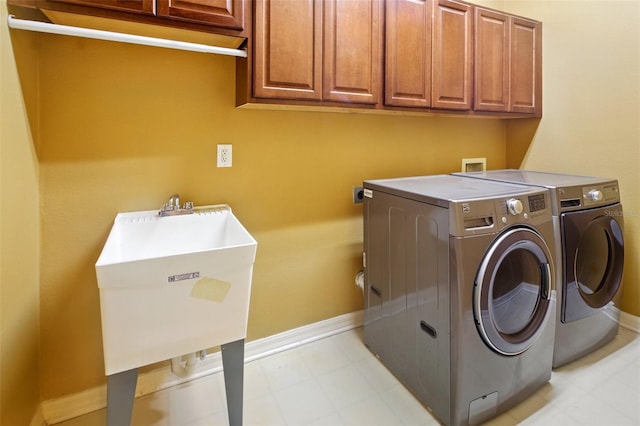 clothes washing area with cabinet space, independent washer and dryer, a sink, baseboards, and light floors