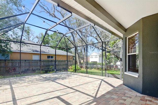 view of patio with fence and a lanai