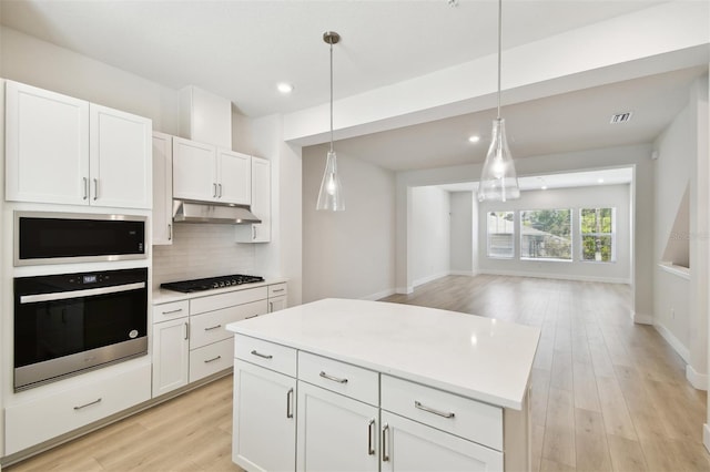 2123 1st Ave N, Saint Petersburg, FL 33713 - kitchen with appliances with stainless steel finishes, light wood finished floors, decorative backsplash, white cabinets, and under cabinet range hood