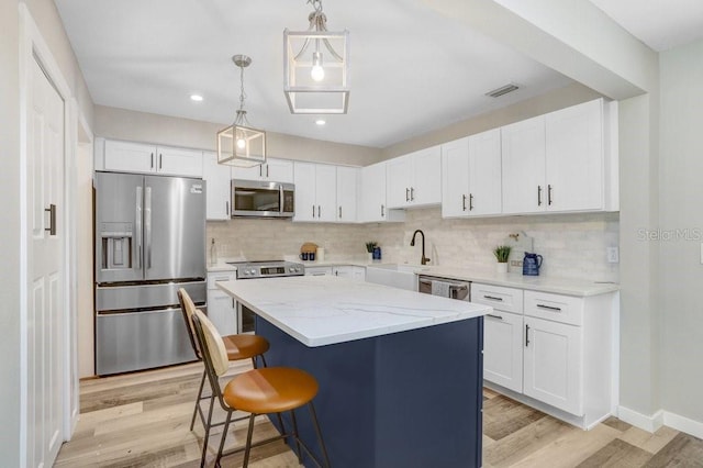 kitchen featuring visible vents, decorative backsplash, white cabinetry, light wood finished floors, and appliances with stainless steel finishes