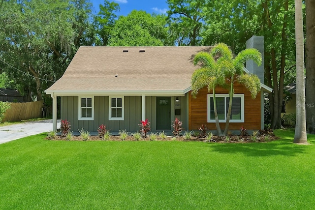 ranch-style house with board and batten siding, fence, a chimney, and a front lawn