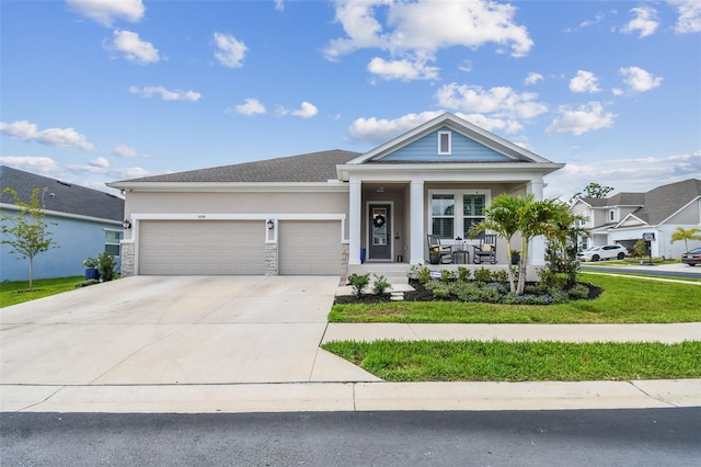 view of front of property with covered porch, an attached garage, driveway, and stucco siding