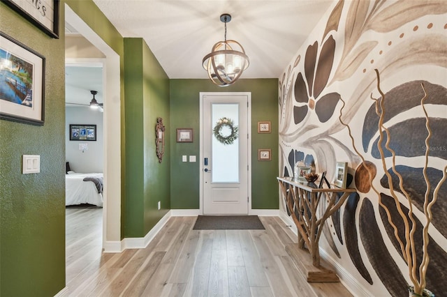 entryway featuring baseboards, ceiling fan with notable chandelier, and wood finished floors