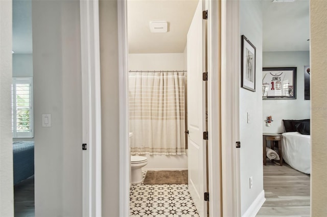 ensuite bathroom featuring toilet, tile patterned floors, ensuite bathroom, and shower / bath combo