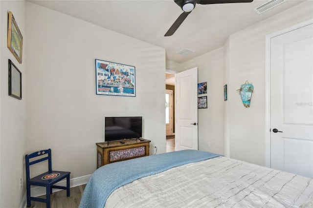 bedroom featuring visible vents, a ceiling fan, baseboards, and wood finished floors