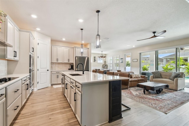 kitchen featuring light wood-style floors, open floor plan, light countertops, a sink, and stainless steel appliances