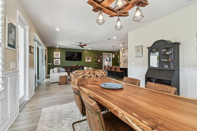 dining room with light wood-style floors, ceiling fan, wainscoting, and recessed lighting