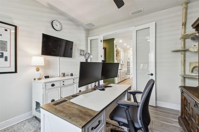 office with baseboards, light wood-style flooring, visible vents, and vaulted ceiling