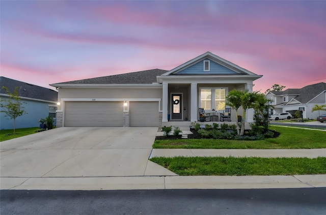 view of front facade with an attached garage, a front lawn, stucco siding, a porch, and driveway