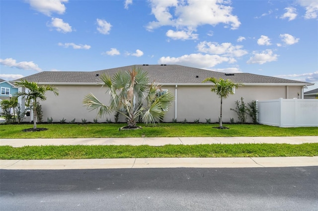 view of side of property with fence, stucco siding, and a lawn