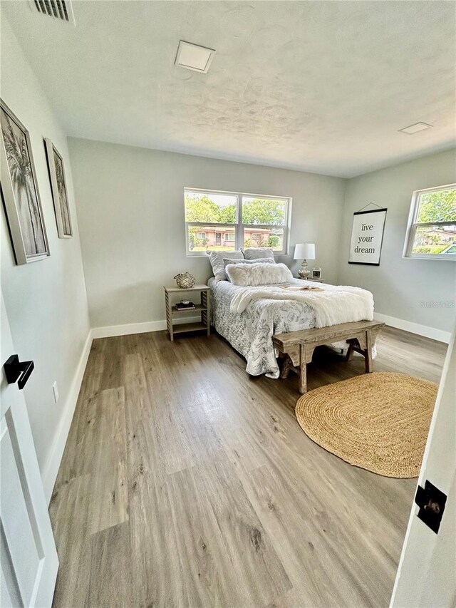 bedroom featuring baseboards, visible vents, and wood finished floors