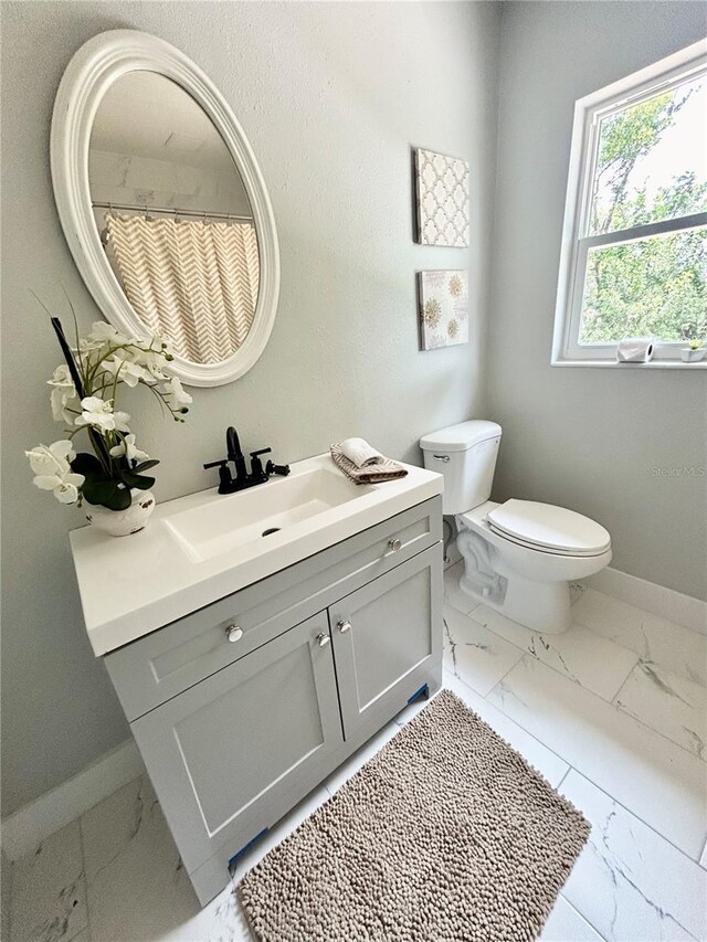 bathroom with toilet, baseboards, marble finish floor, and vanity