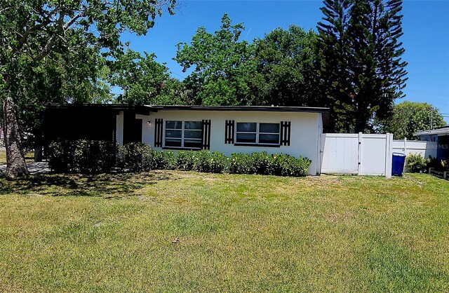 view of front of house with stucco siding, a gate, a front lawn, and fence