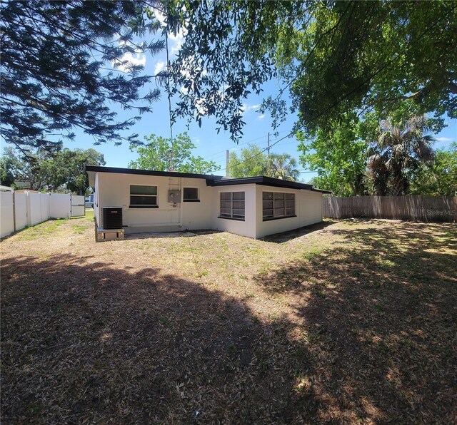 rear view of house featuring a fenced backyard, central AC unit, and stucco siding