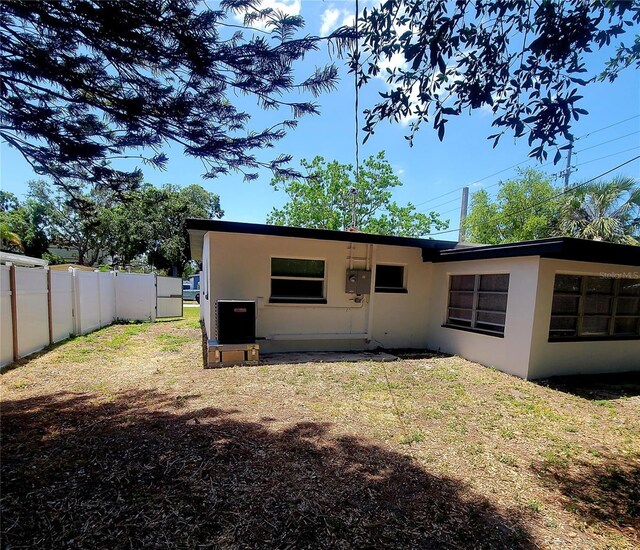 back of property with fence, stucco siding, and a lawn